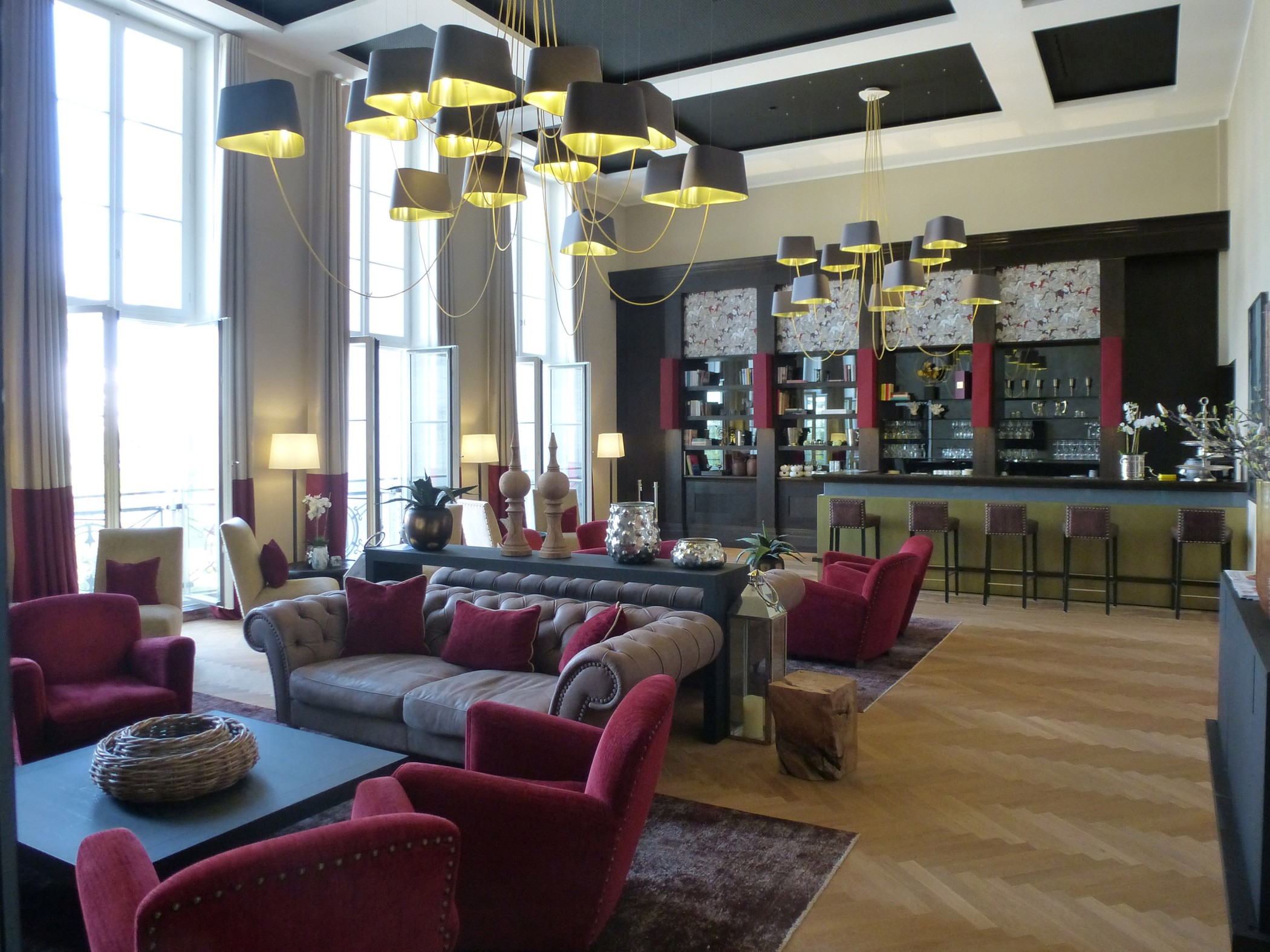 Club lounge in the Sophienpalais with red armchairs, a Chesterfield sofa, chandeliers and a bar