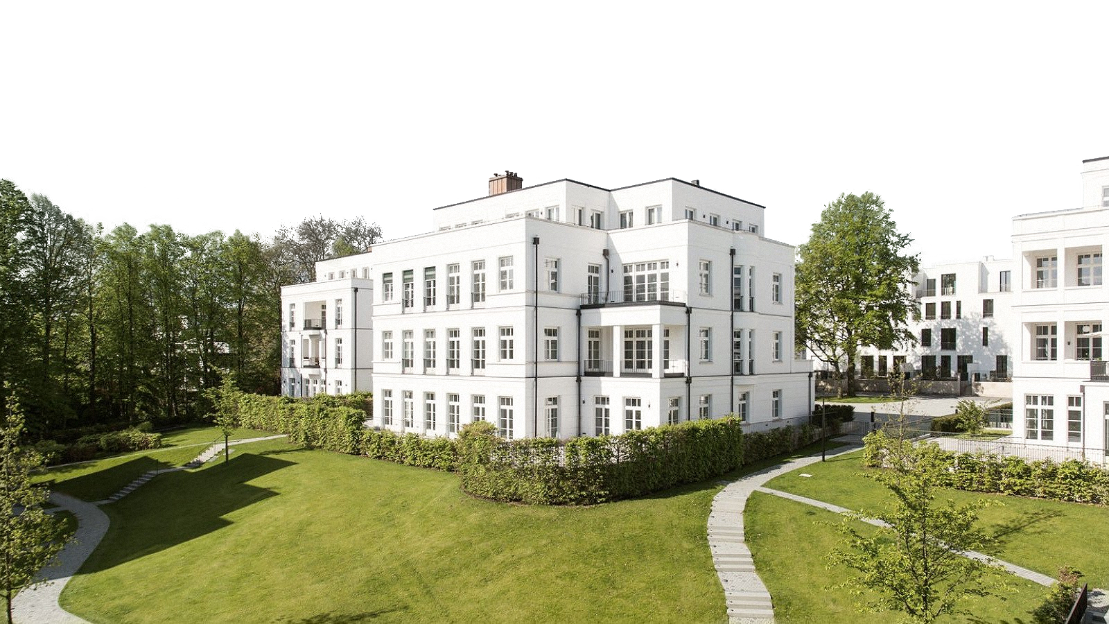 Weiße Villen im klassischen Stil an einem großen Parkgarten mit Rasenflächen, Hecken und geschwungenen Wegen