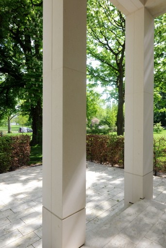 Helle Natursteinpfeiler einer Loggia der Alstervillen mit Plattenboden und Blick auf Hecke, Bäume und Garten