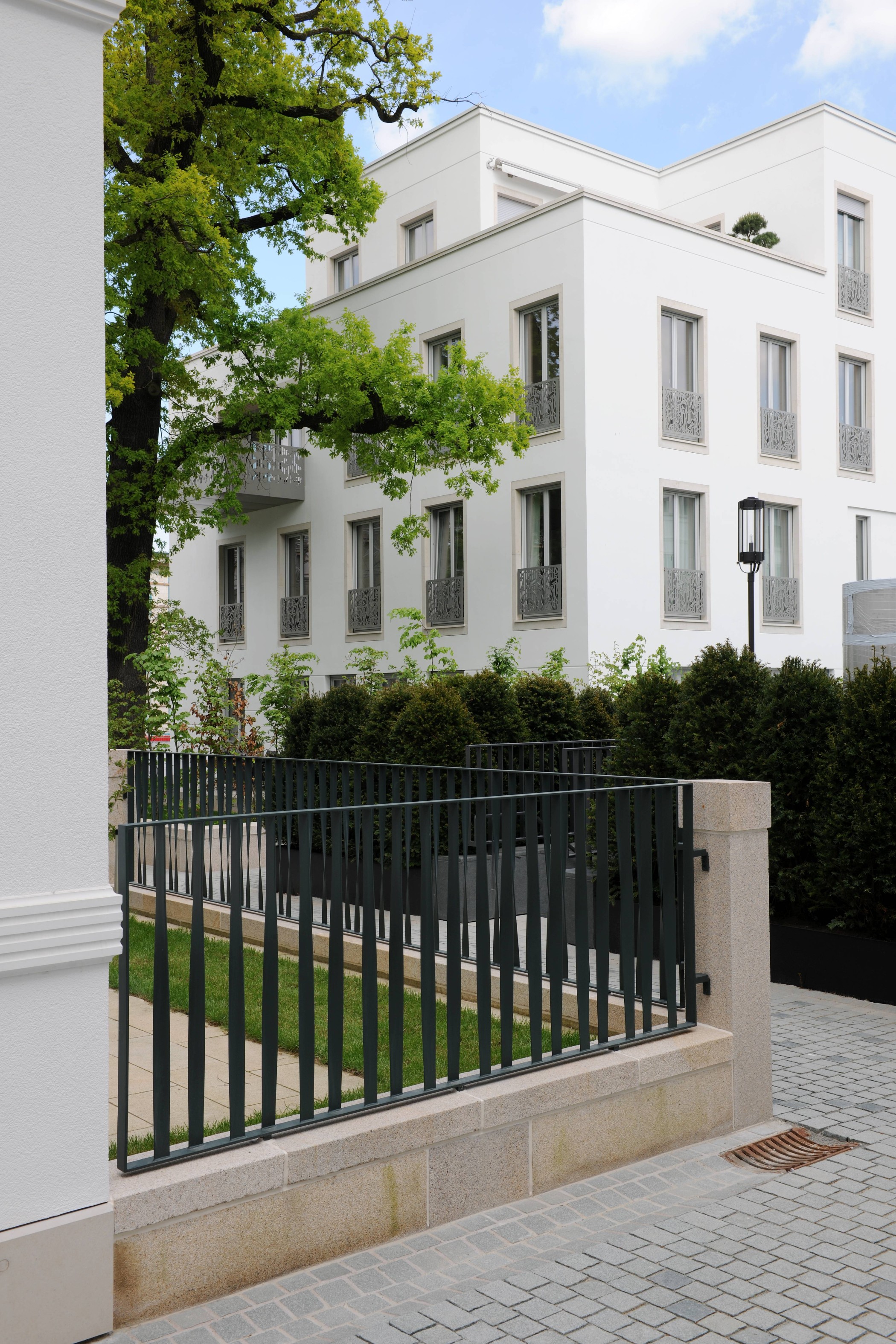 Fassadenansicht der Sophienterrassen in Hamburg Harvestehude mit weißer Architektur, schmiedeeisernen Balkondetails und angrenzendem Gartenbereich