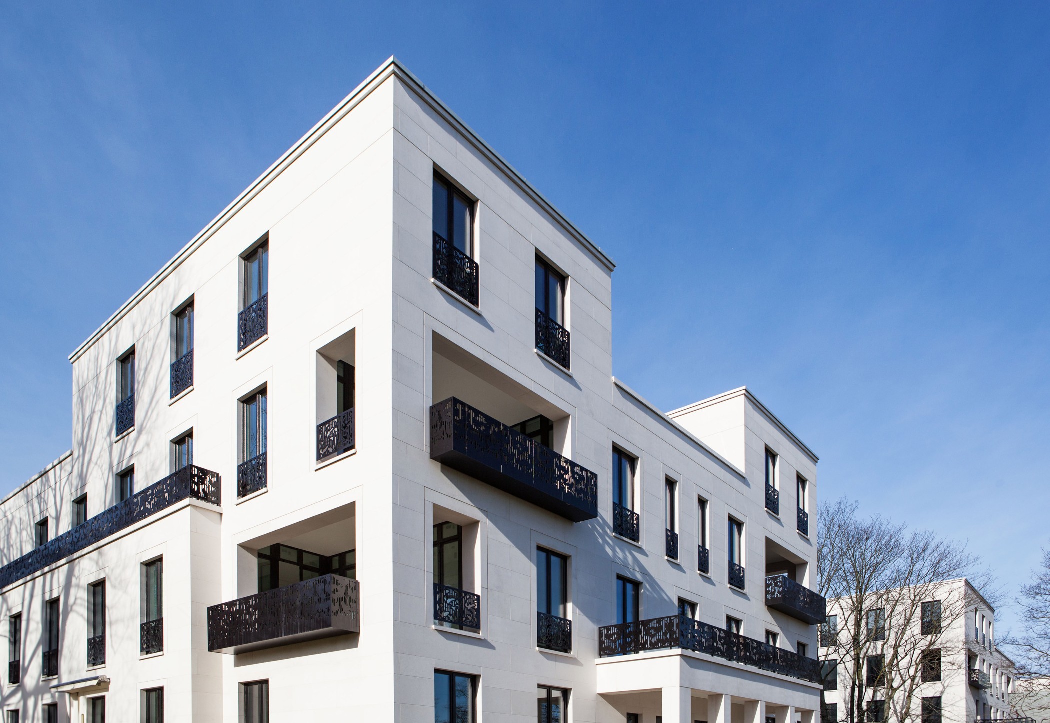 White villa of the Alster villas with ornamental black balcony railings against a blue sky, seen from below