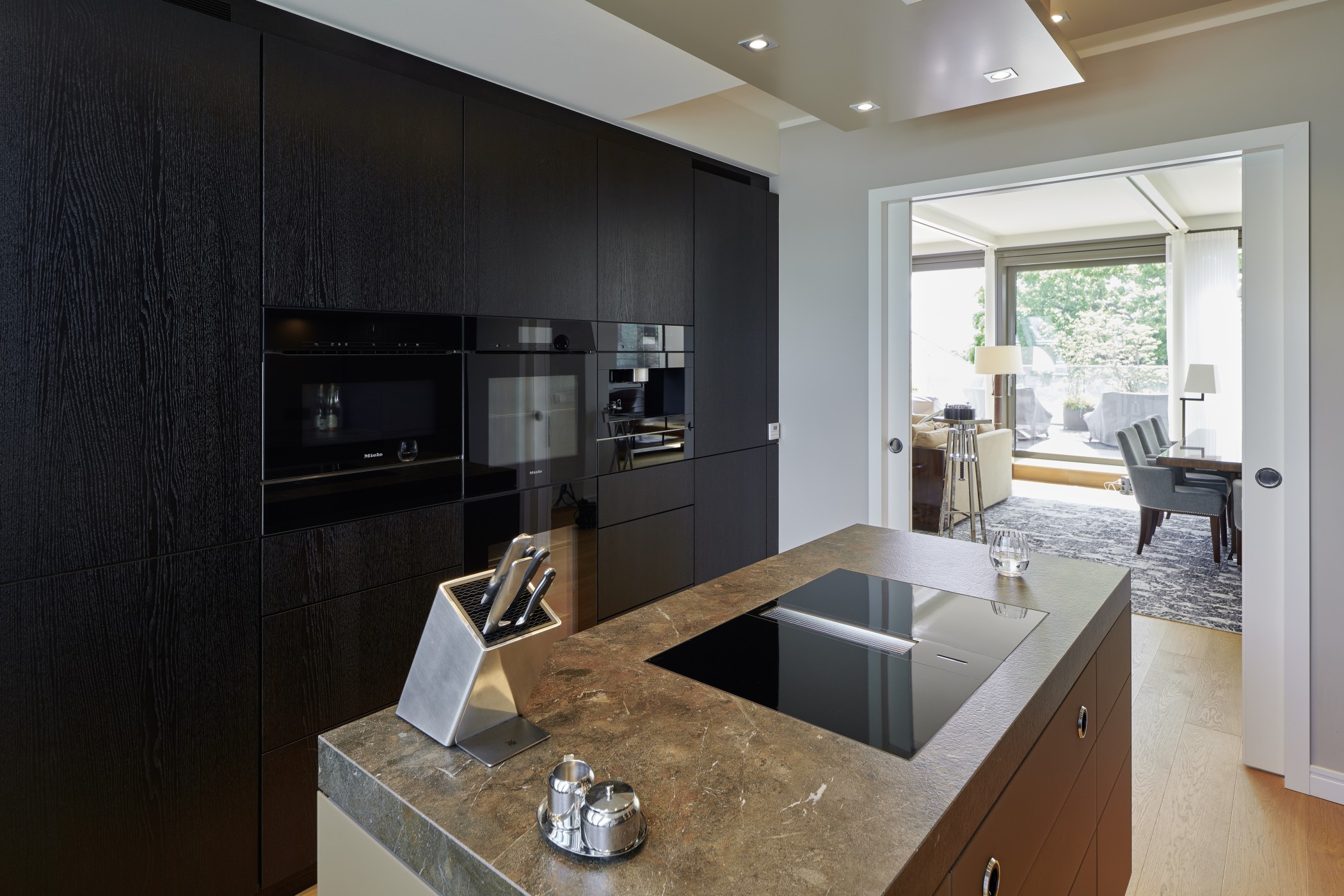 Moderne Designer-Küche der Sophienterrassen in Hamburg Harvestehude mit hochwertiger Einbauausstattung und Blick in den offenen Wohnbereich