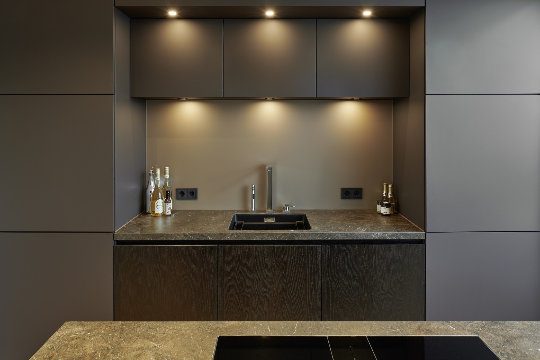 Hochwertiges Küchendetail der Sophienterrassen in Hamburg Harvestehude mit eleganter Steinplatte, Einbauschränken und moderner Beleuchtung
