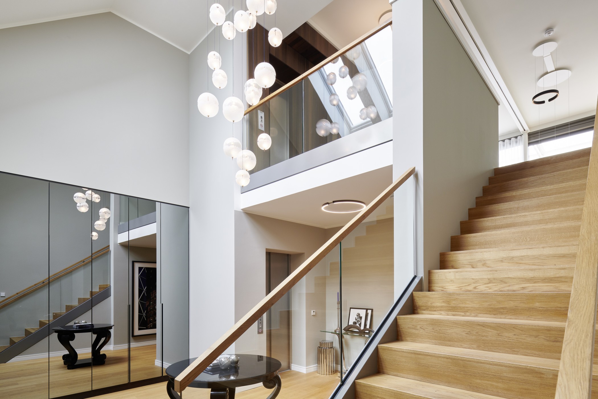 Exklusives Treppenhaus der Sophienterrassen in Hamburg Harvestehude mit gläsernem Geländer, moderner Lichtinstallation und großzügiger Galerie.