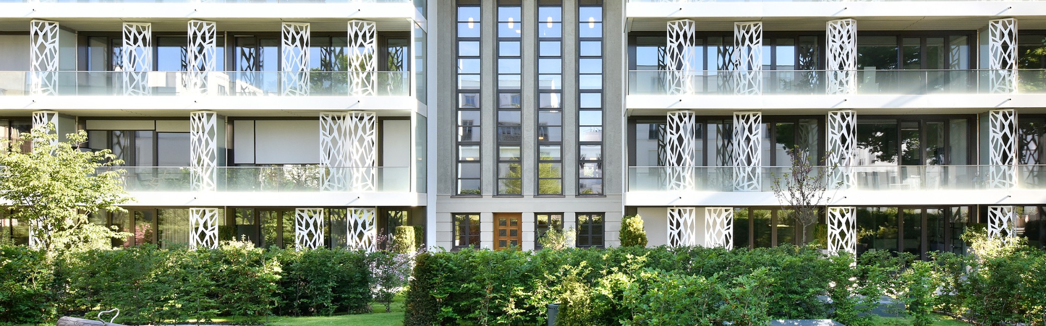 Moderne Fassadenansicht der Sophienterrassen in Hamburg mit großzügigen Glasbalkonen, dekorativen Metallpanelen und Blick auf die alte Eiche – hochwertige Architektur einer exklusiven Luxusimmobilie