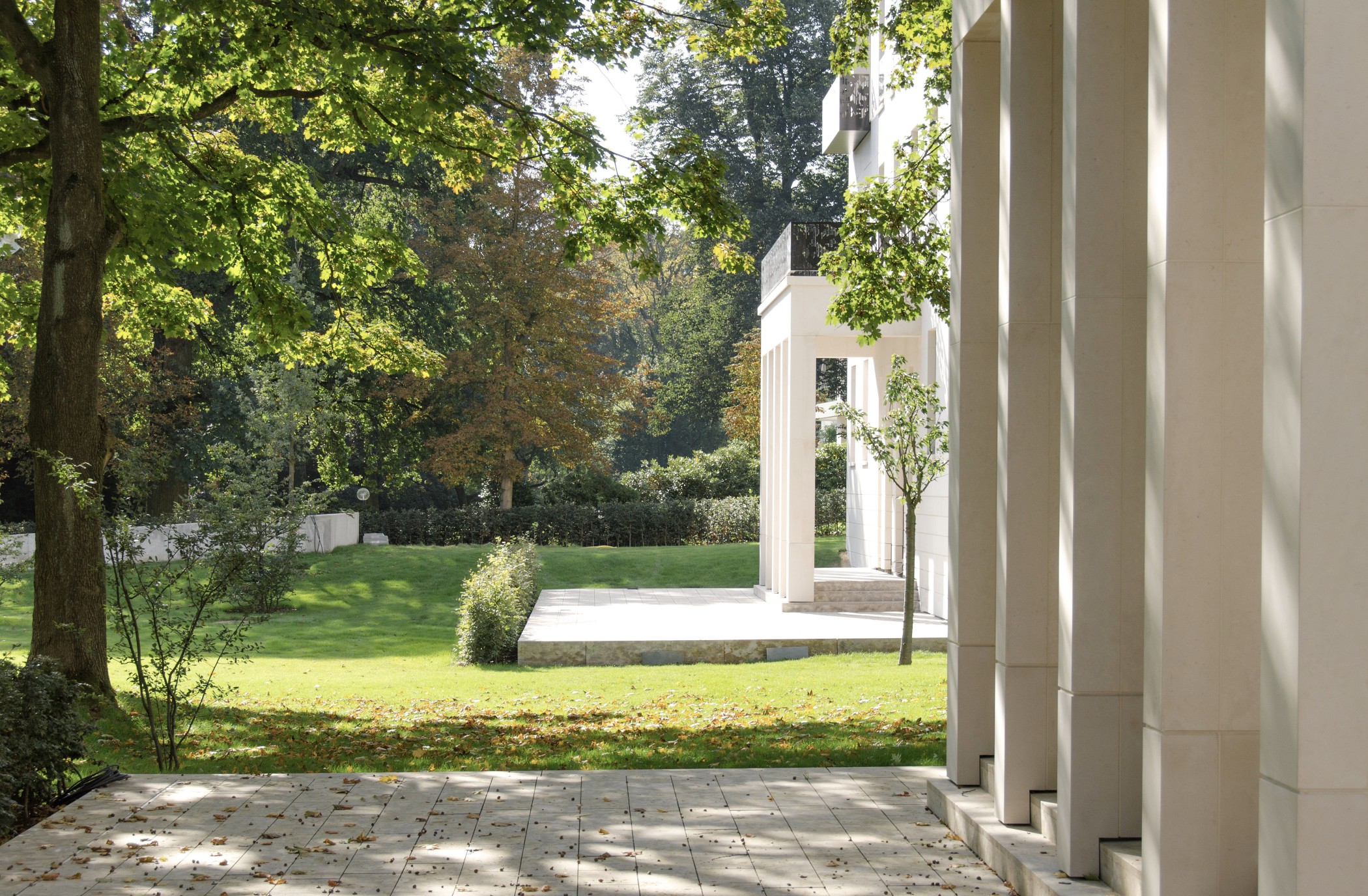 Blick vom Säulenportikus der Sophienterrassen auf den weitläufigen Garten – harmonisches Zusammenspiel von Natursteinarchitektur und grüner Parklandschaft in einer Hamburger Luxusimmobilie